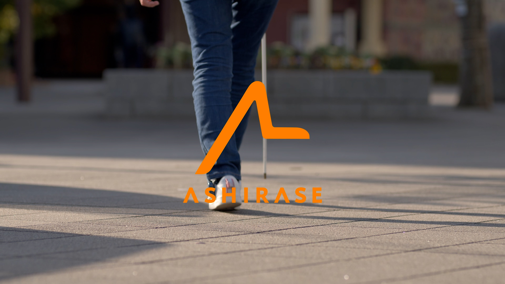 A person walking with ASHIRASE device and white cane