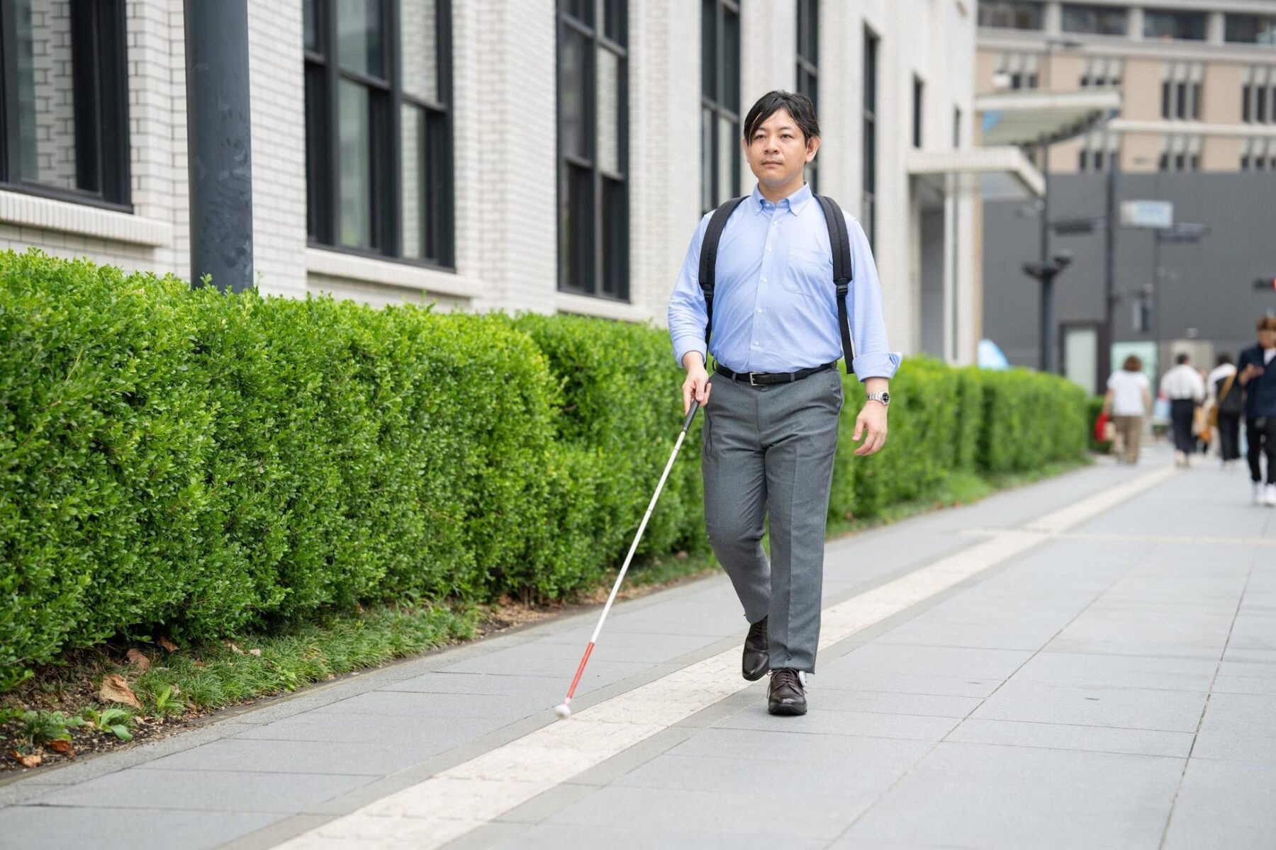 あしらせを装着した靴を履き白杖を持った男性