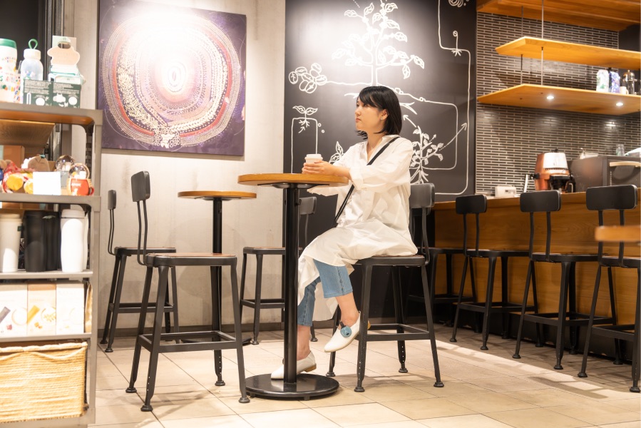 カフェの椅子に座ってくつろぐ女性の画像